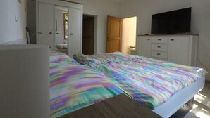 A bedroom with a bed, a wardrobe, a television, and a ceiling fan. - Comfortable apartment on the Sturmhof (Grefrath)