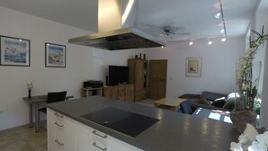 A modern kitchen with a central island, wooden cabinets, and a dining area with a sofa and table. - Comfortable apartment on the Sturmhof (Grefrath)