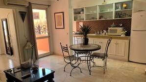 A compact living space with a dining area, kitchen, and a sliding glass door leading to an outdoor area. - CHARMING APARTMENT QUIET COMFORTABLE 2 PLACES C CENTER MARRAKECH GUELIZ (marrakech)