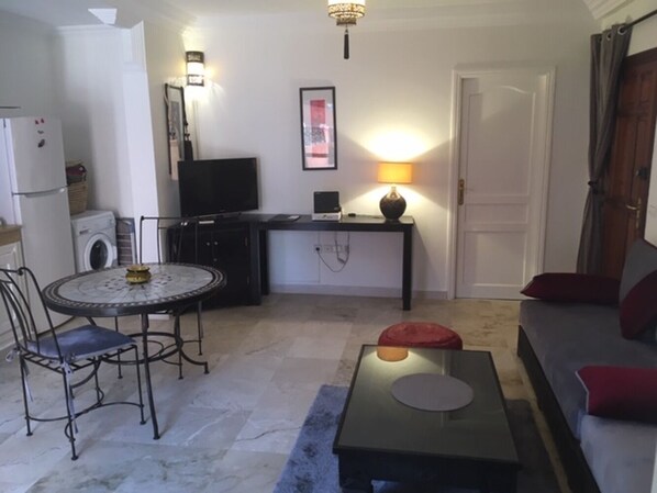 Un espacio habitable compacto con una mesa de comedor, un sofá, un televisor y una lámpara.