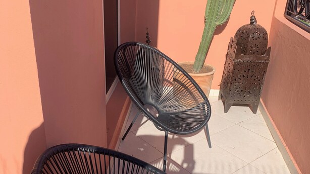 A balcony with two black wire mesh chairs, a cactus, and a decorative metal lantern. - CHARMING APARTMENT QUIET COMFORTABLE 2 PLACES C CENTER MARRAKECH GUELIZ (marrakech)