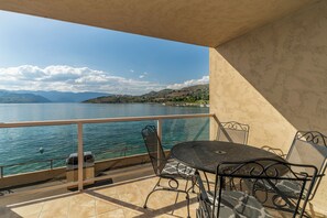 A balcony with a table and chairs overlooking a lake with mountains in the background. - Grandview 522 Waterfront condo on Lake Chelan (Chelan)