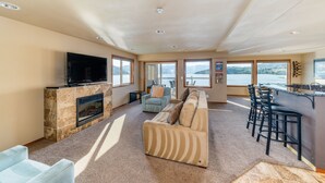A spacious living area with a fireplace, a sofa, a TV, and a bar area with stools. - Grandview 530 Waterfront condo (Chelan)