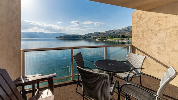 A balcony with a table and chairs overlooking a lake and mountains. - Grandview 530 Waterfront condo (Chelan)