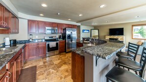 A modern kitchen with granite countertops, stainless steel appliances, and wooden cabinets. - Grandview 530 Waterfront condo (Chelan)