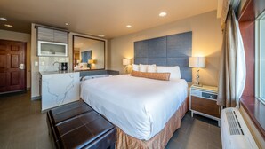 A modern hotel room with a large bed, a built-in desk, a mirror, and a view of the city. - Grandview 710 Waterfront King with River View (Chelan)