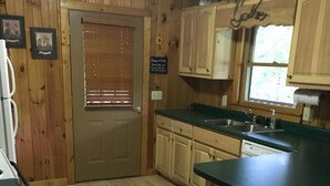 A wooden-paneled kitchen with a central island, a built-in sink, and a window above the sink.