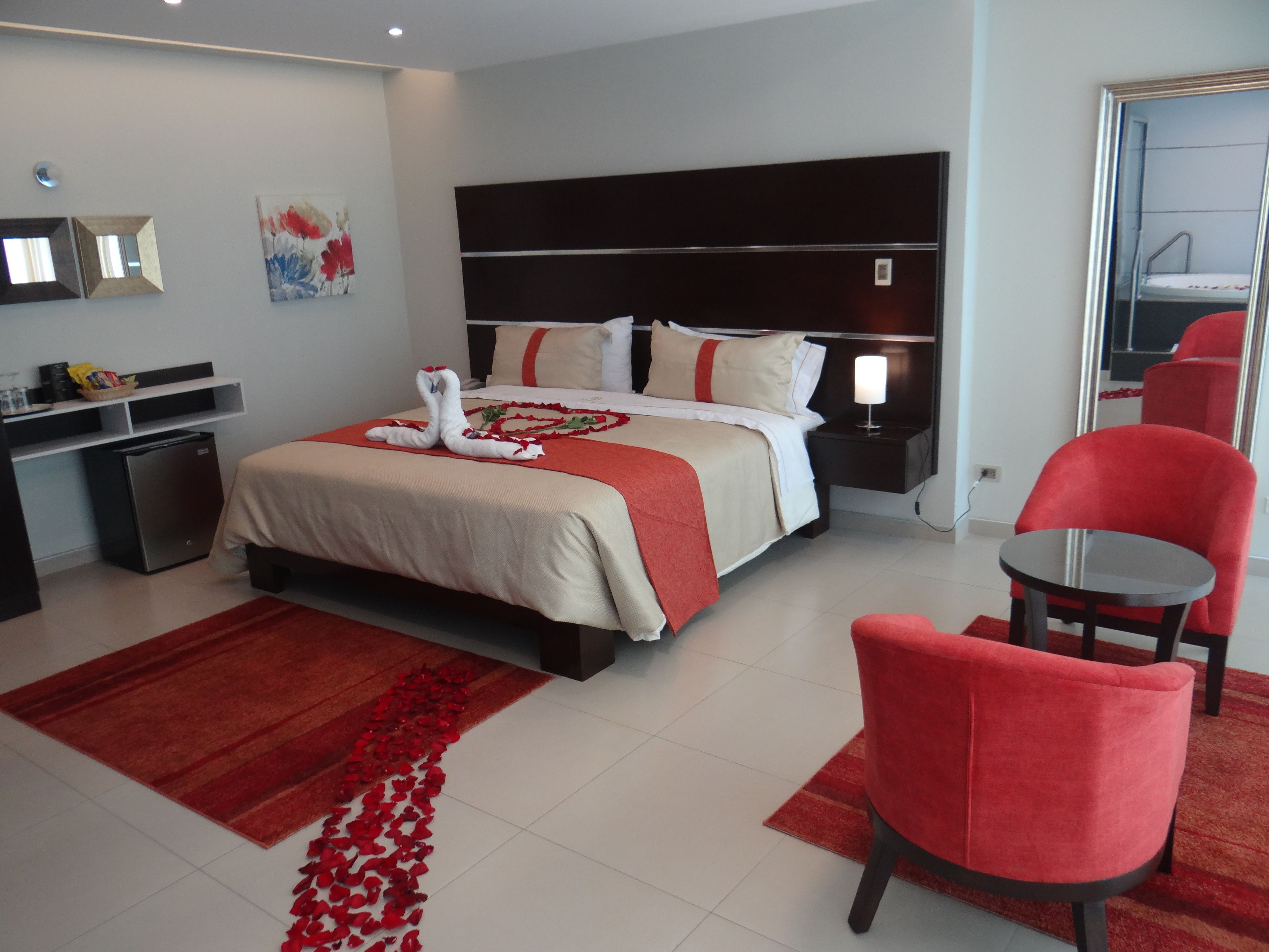 A hotel room with a bed, a desk, a chair, and a small table.