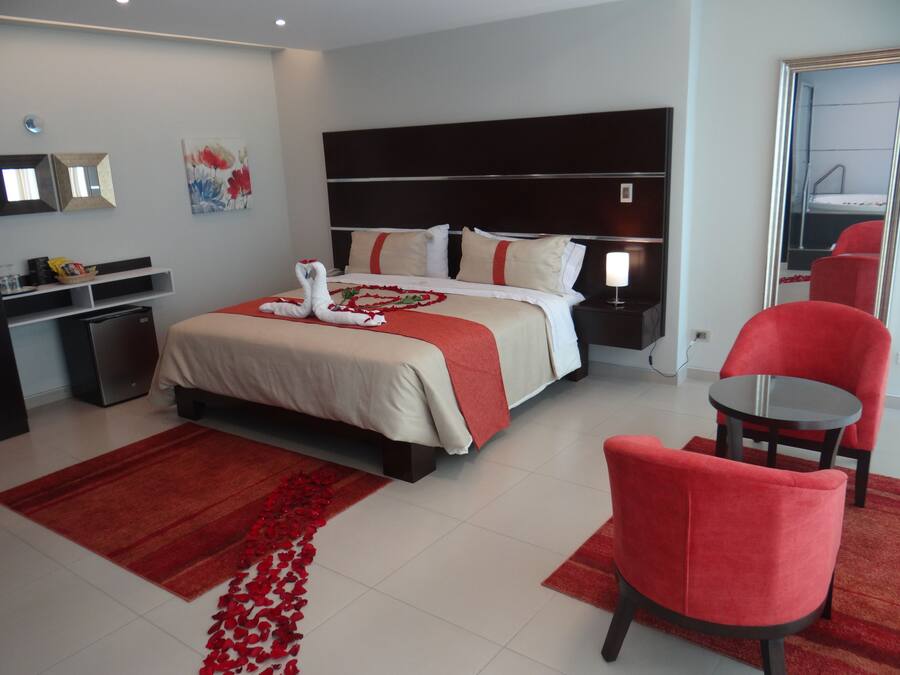 A hotel room with a bed, a desk, a chair, and a small table.