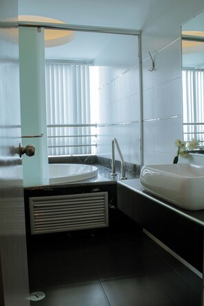 A modern bathroom with a large mirror, a sink, and a shower area. - Verona Hotel & Baños Turcos (Lima)