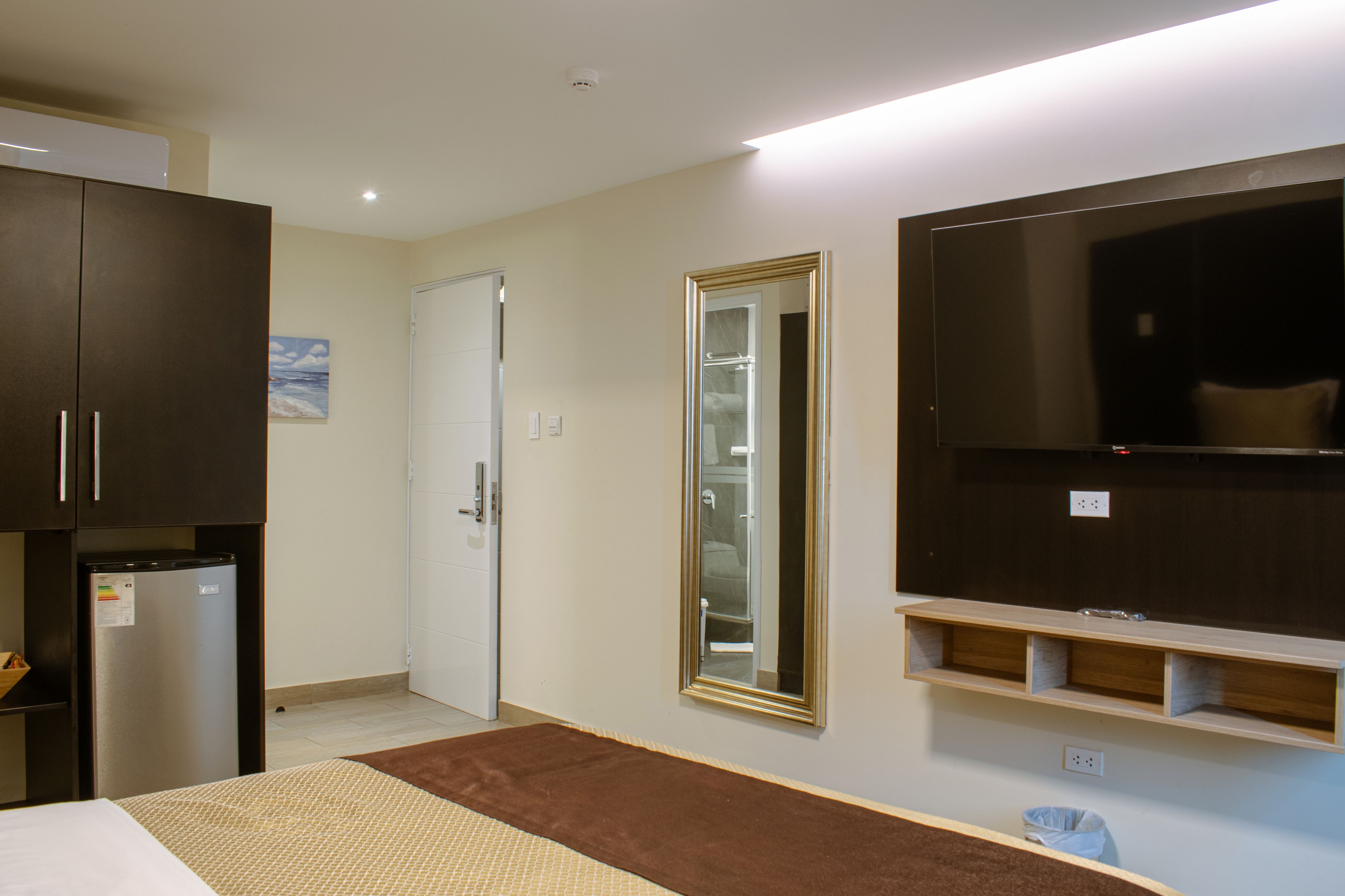 A modern hotel room with a bed, a TV, a wardrobe, and a bathroom visible through a door.