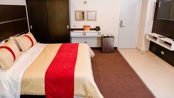 Une chambre d’hôtel équipée d’un lit, d’un bureau, d’une télévision et d’une armoire.