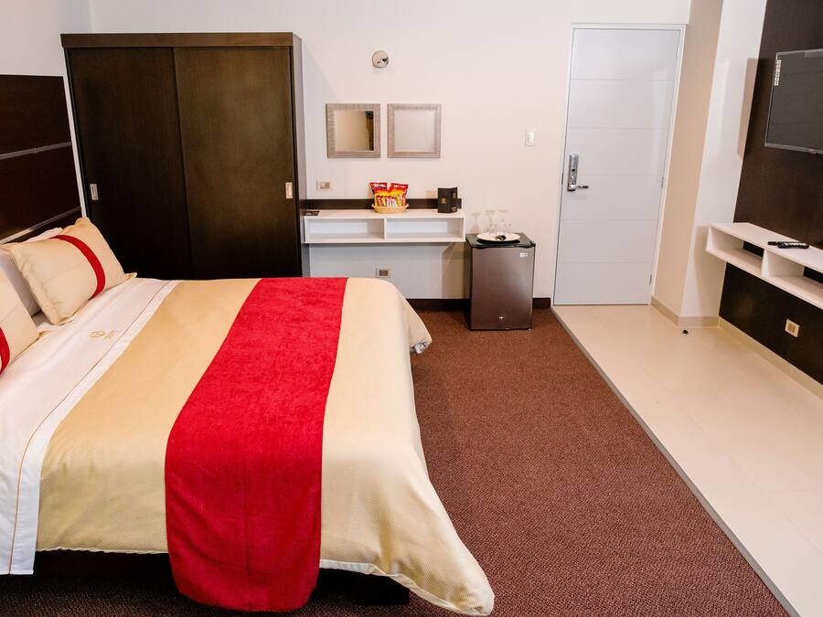 Une chambre d’hôtel équipée d’un lit, d’un bureau, d’une télévision et d’une armoire.