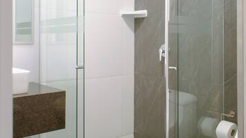 Un baño moderno con cabina de ducha de vidrio, suelo de mármol y retrete blanco.