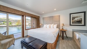 Een moderne hotelkamer met een groot bed, een zithoek, uitzicht op het water en een badkamer met bad.