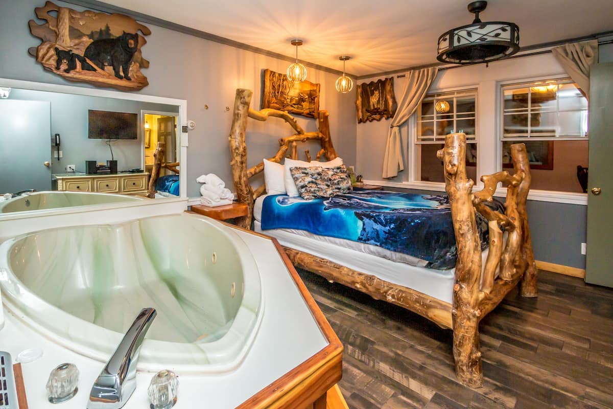 A bedroom with a large wooden bed, a bathtub, and a painting of a bear on the wall.
