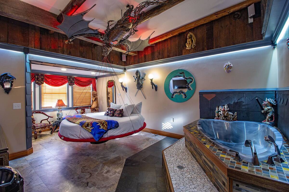 A spacious bedroom with a large bed, a bathtub, and a wooden ceiling.