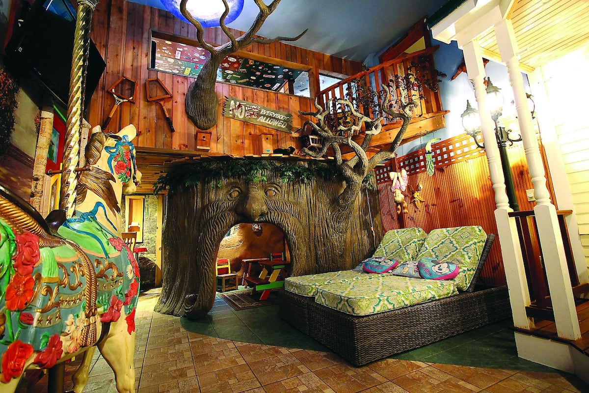 A cozy room with a large tree sculpture, a wicker sofa, and a small table.