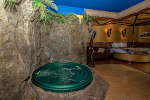 A spa area with a hot tub, a wooden bench, and a thatched-roof structure. - Adventure Suites (North Conway)