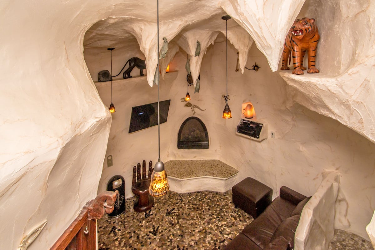 An interior with a cave-like design, featuring a fireplace, seating area, and decorative animal figures.