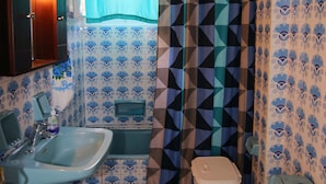 Et lille badeværelse med vask, toilet og badeforhæng.