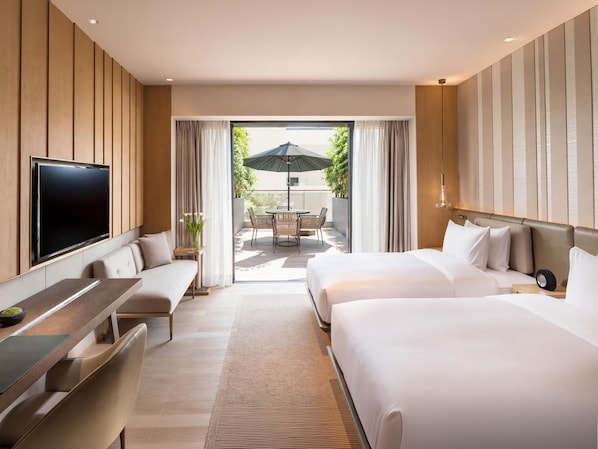 Une chambre d’hôtel moderne dotée d’une télévision à écran plat, d’un canapé, d’un lit et d’un balcon avec coin salon extérieur.
