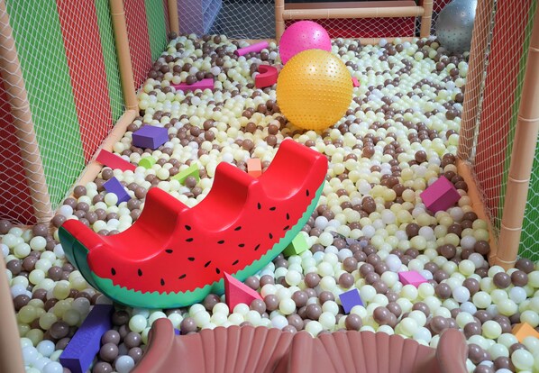 Un área de juegos con un tobogán, pelotas y diversas formas.