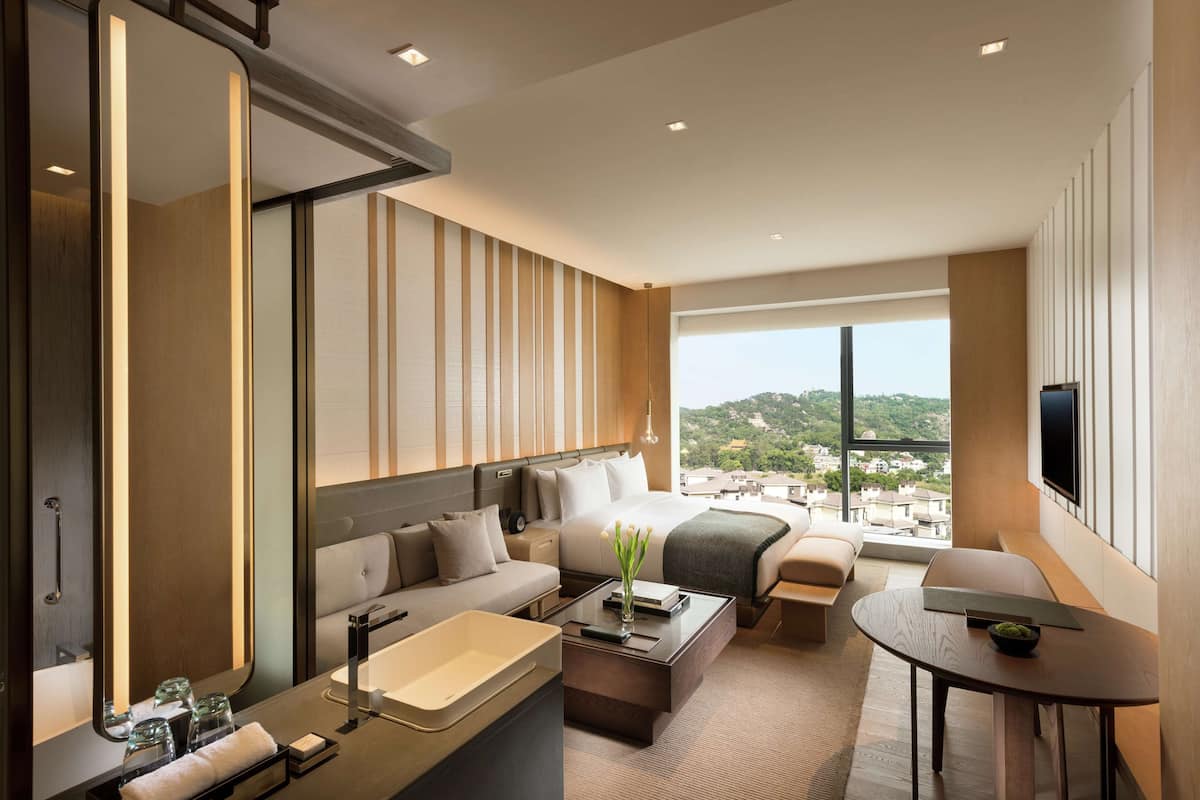 Une chambre d’hôtel moderne avec un grand lit, un canapé, une table basse et un téléviseur.