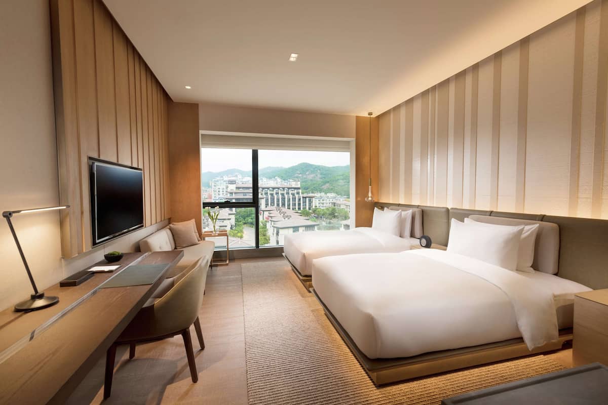 Une chambre d’hôtel avec un grand lit, un bureau, une chaise, une télévision et une vue sur la ville.