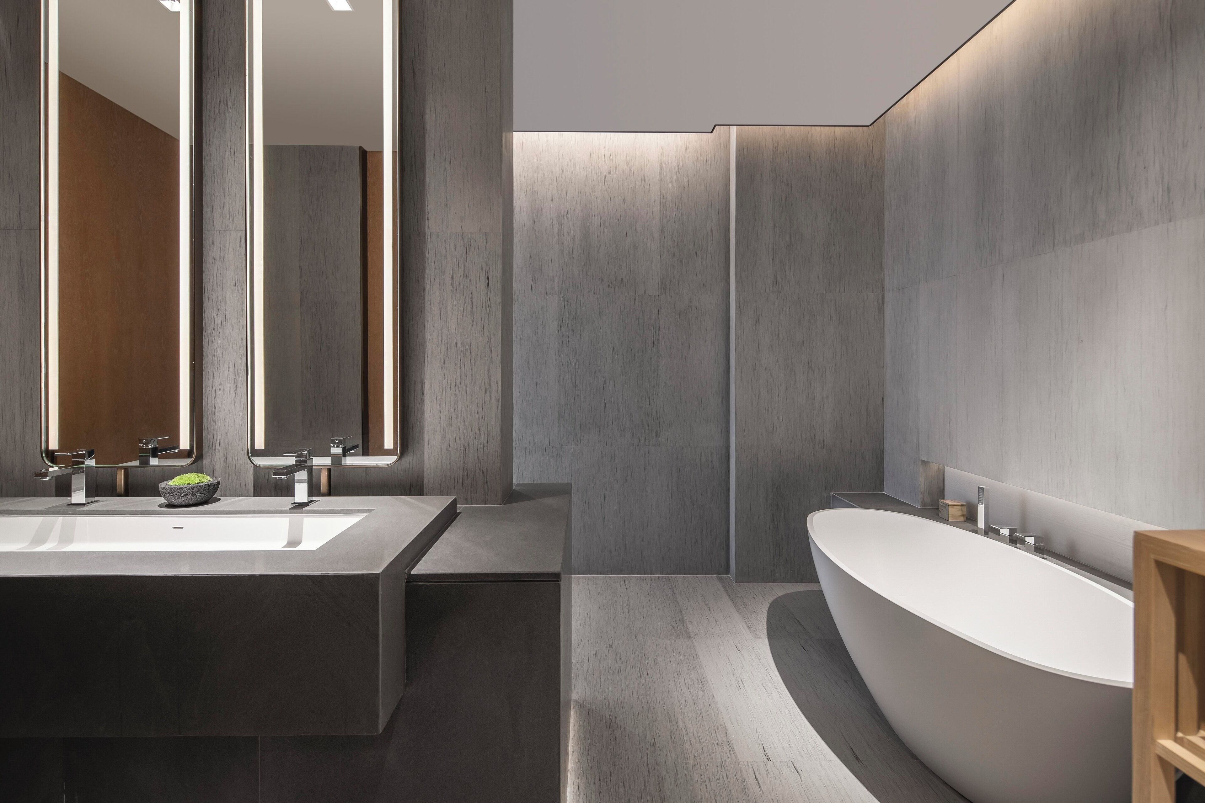 A modern bathroom with a large rectangular sink, a freestanding bathtub, and a mirror above the sink.