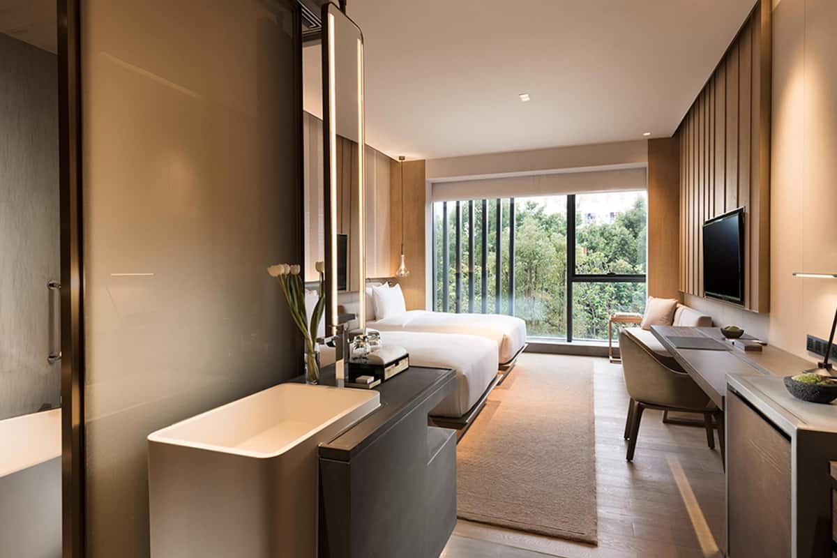 Une chambre d’hôtel moderne dotée d’un grand lit, d’un espace bureau séparé, d’un grand miroir et d’un téléviseur fixé au mur.