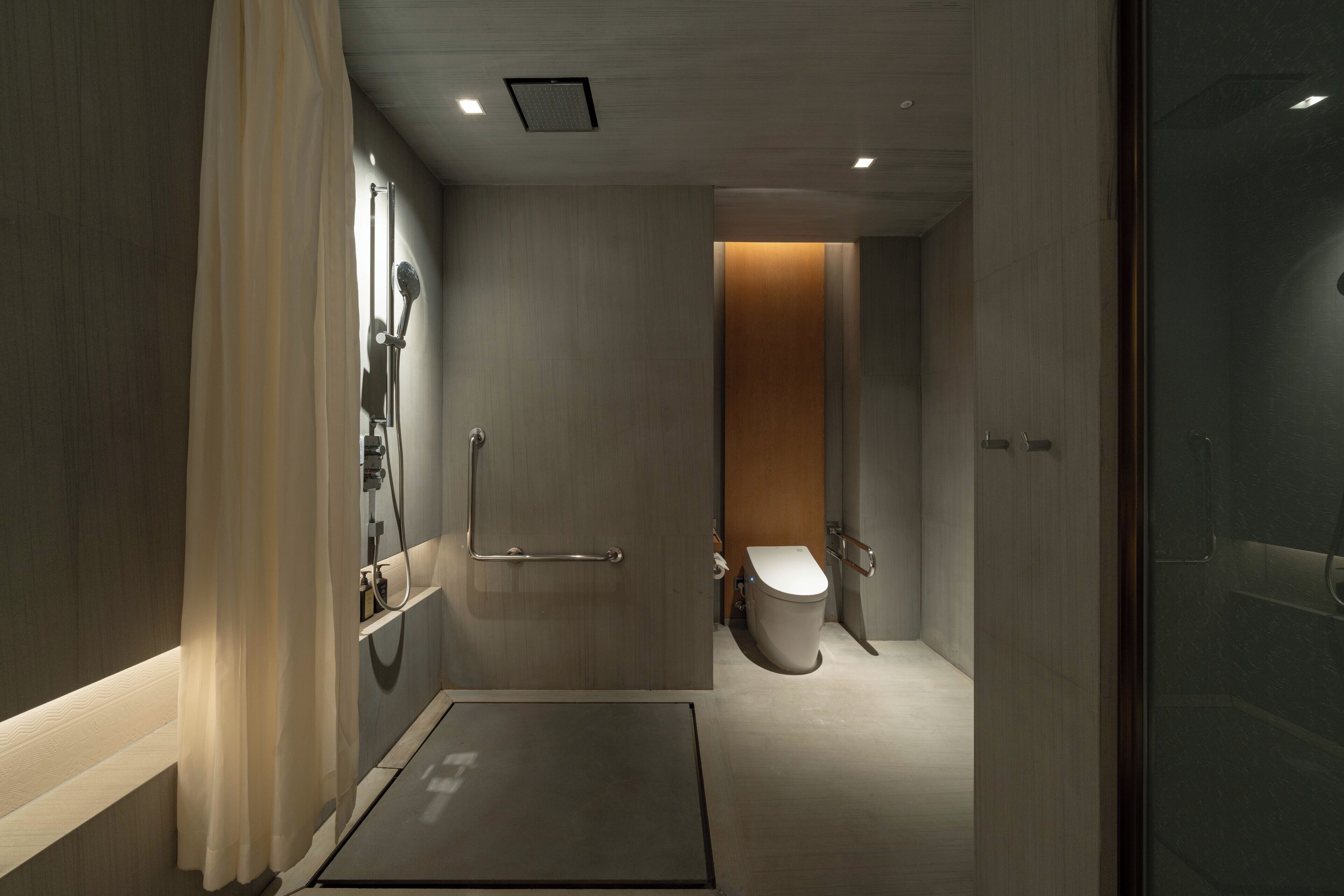 A modern bathroom with a shower, toilet, and a glass partition.