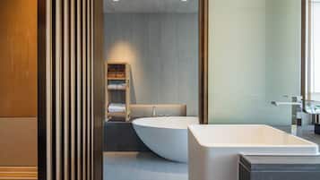 Une salle de bain moderne avec une baignoire sur pieds, un meuble-lavabo en bois et une étagère intégrée où sont rangées les serviettes.