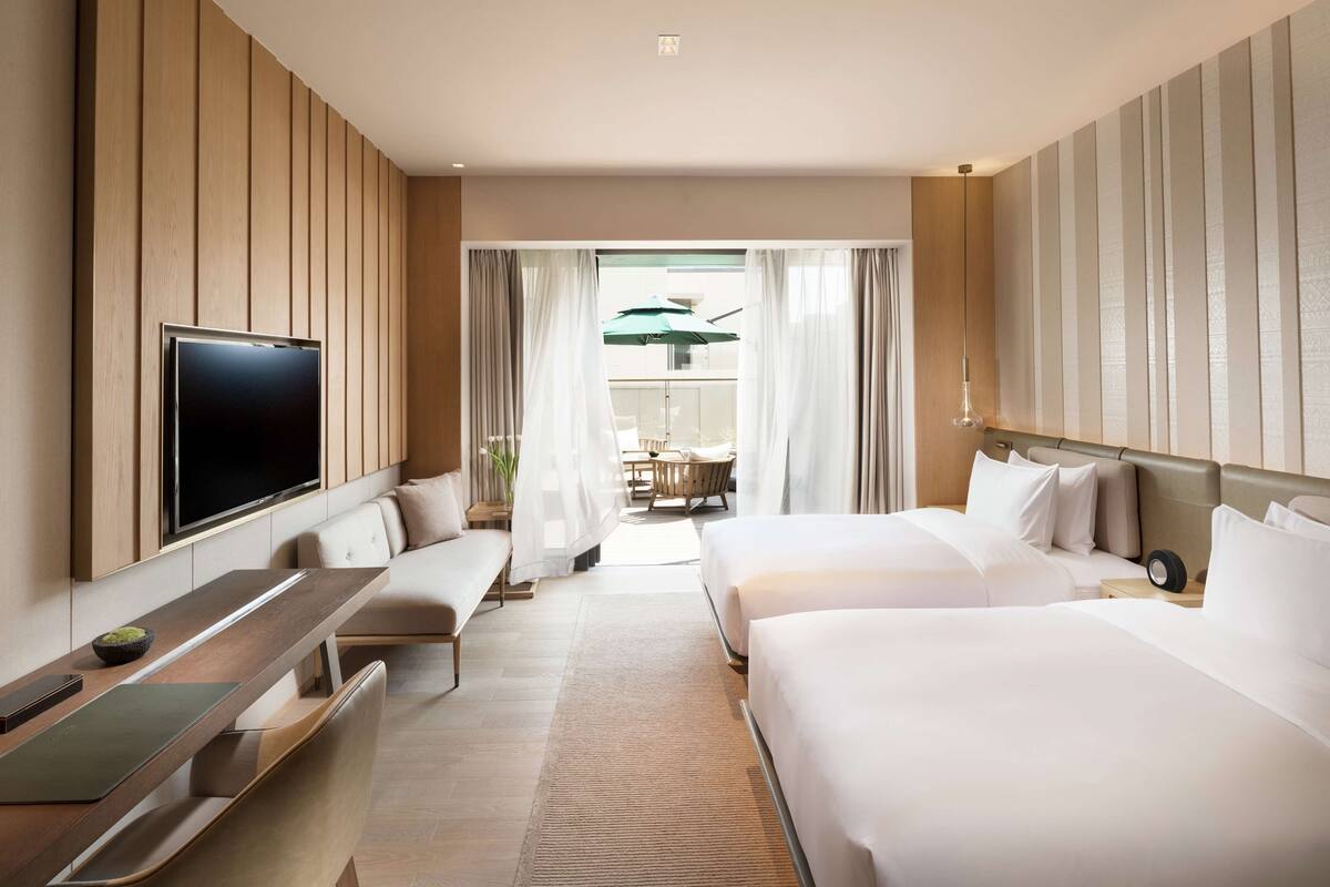 Une chambre d’hôtel avec deux lits, une télévision, un bureau et un balcon avec vue.