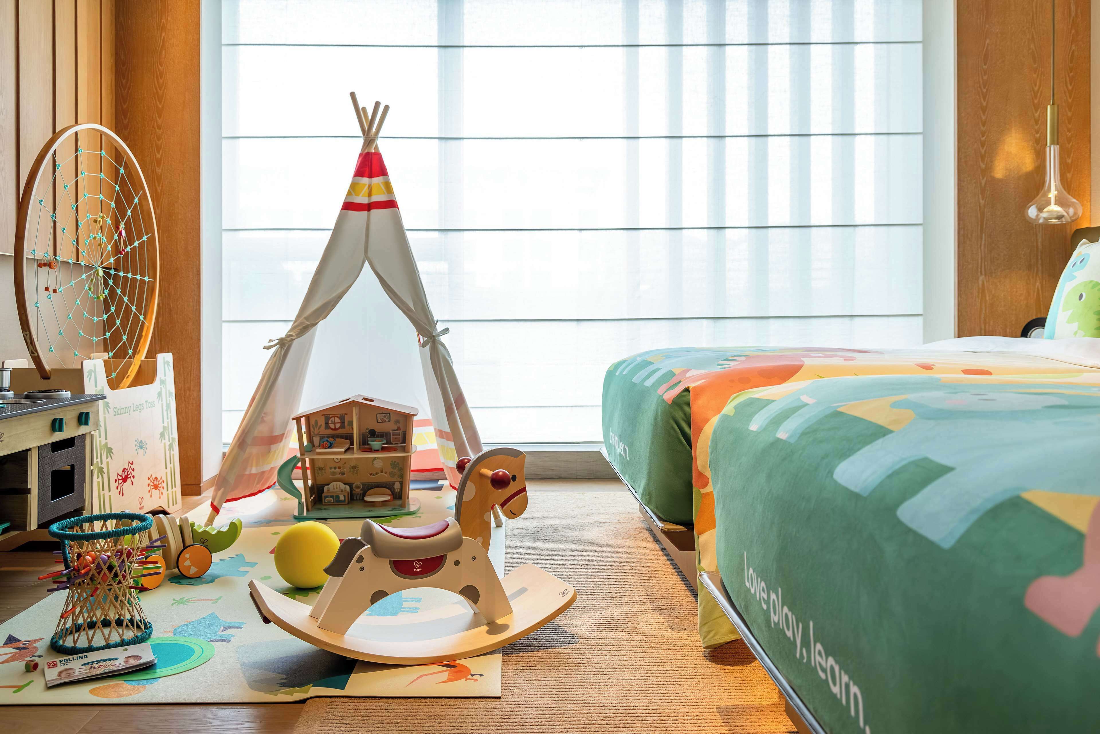 A child's play area with a teepee, rocking horse, and various toys.