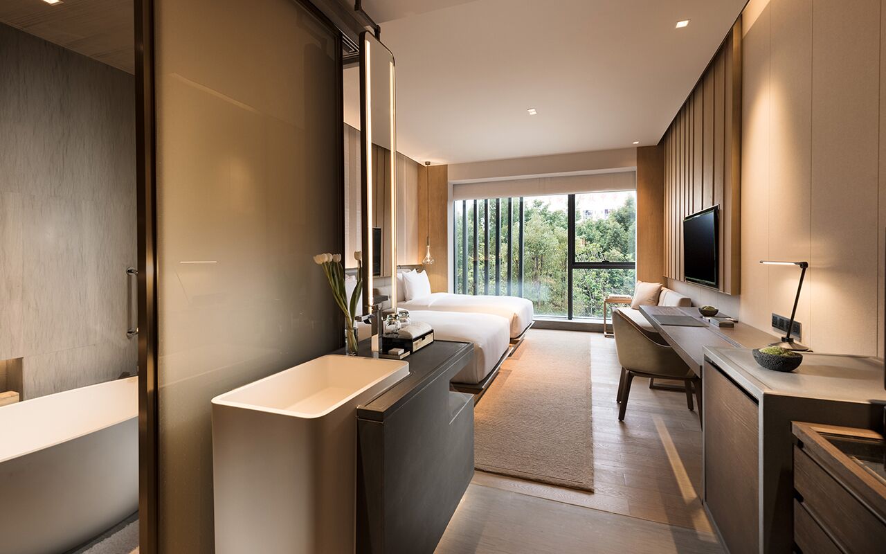 A modern hotel room with a large bed, a desk, a bathroom, and a TV.
