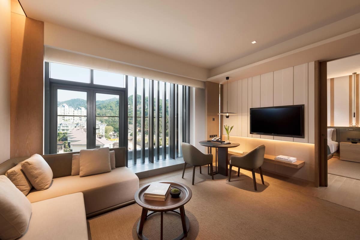 Une chambre d’hôtel moderne équipée d’un canapé, d’une table basse ronde, d’un téléviseur et d’un coin repas avec des chaises.