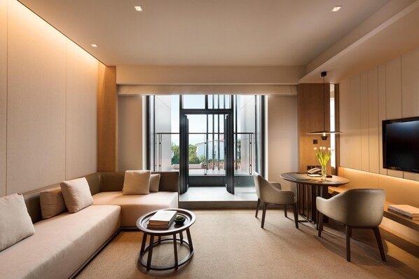 Ein modernes Wohnzimmer mit Sofa, Couchtisch, Fernseher und Blick auf einen Balkon.
