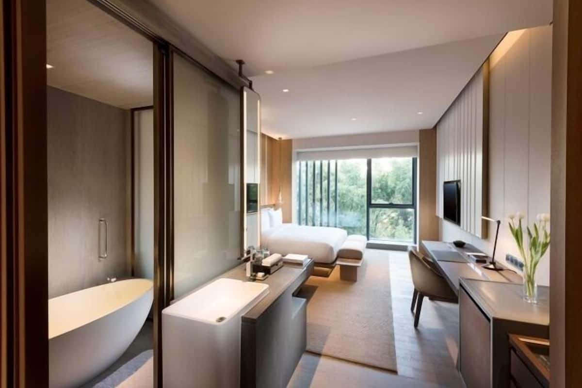 Une chambre d’hôtel moderne dotée d’un grand lit, d’un coin salon, d’une baignoire et d’un téléviseur.
