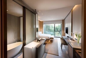 Ein modernes Hotelzimmer mit einem großen Bett, einer Sitzecke, einer Badewanne und einem Fernseher.