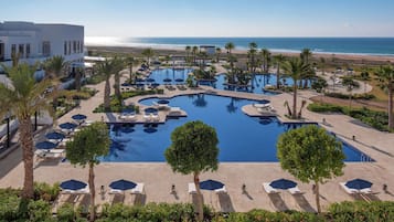 Een buitenzwembad, parasols bij het zwembad en ligstoelen