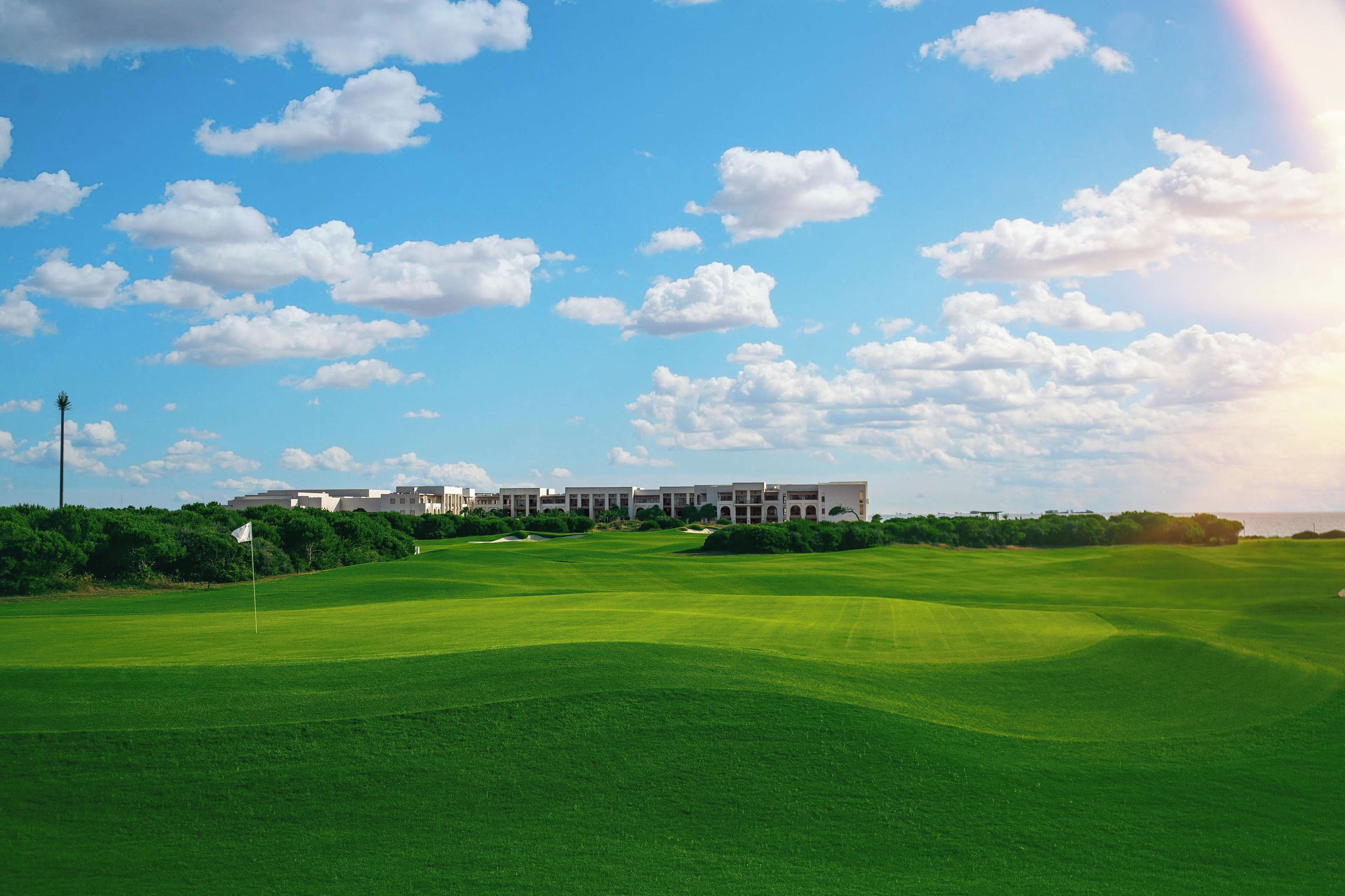 Um campo de golfe com um clube de campo ao fundo.