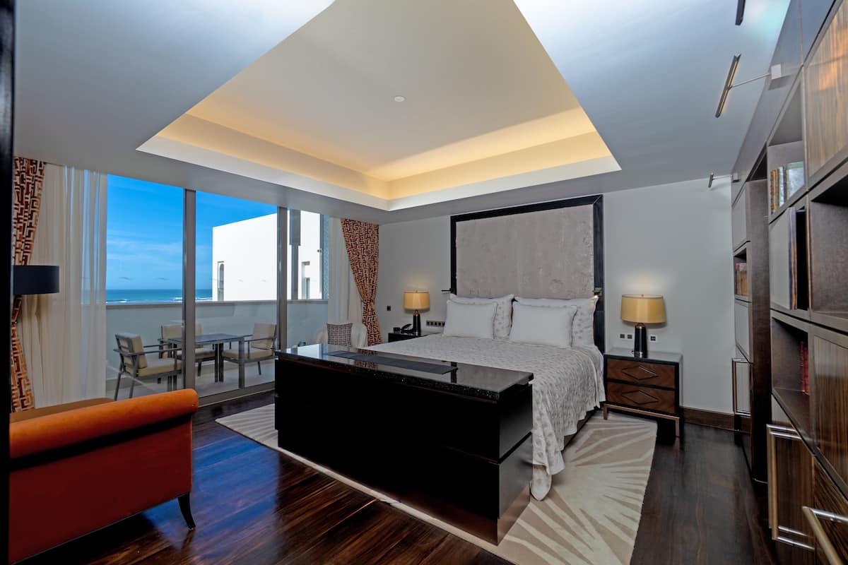Une chambre moderne avec un grand lit, un bureau et une vue sur l’océan.