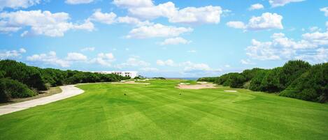A golf course with a clear sky and scattered clouds.