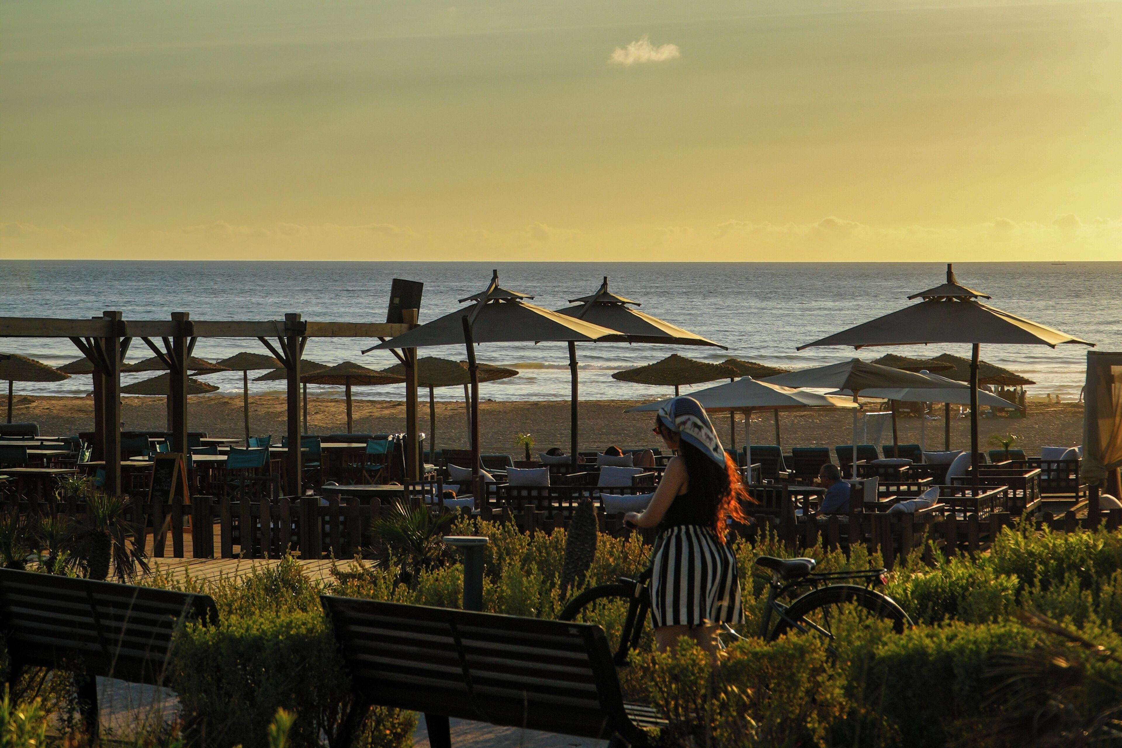 A beachside café with outdoor seating and umbrellas, overlooking the ocean.