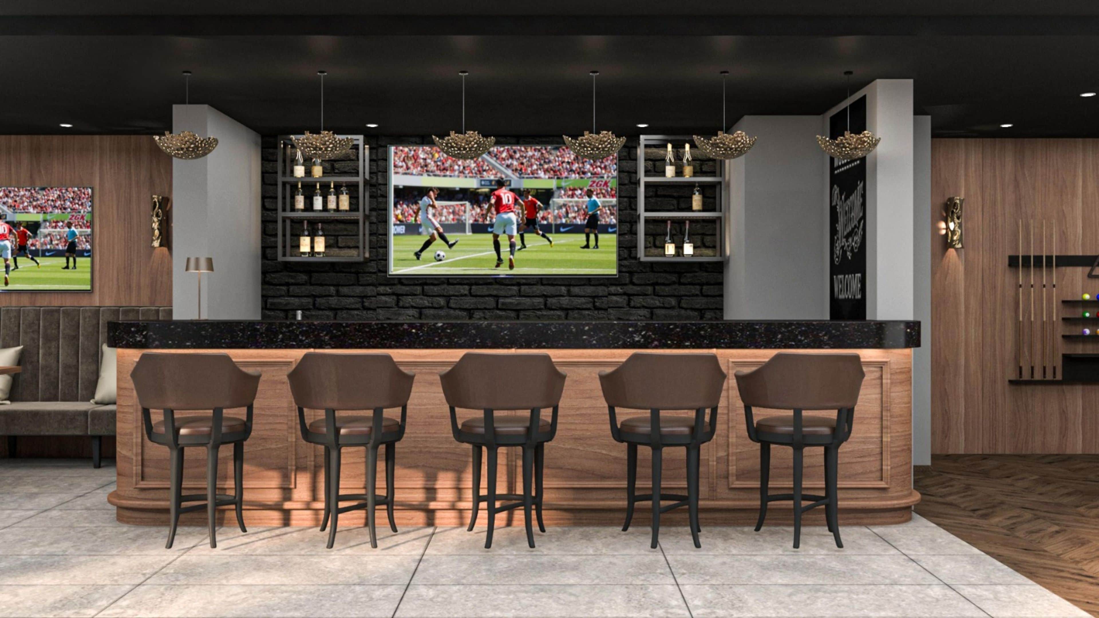 Zona de bar con pared de piedra, taburetes y una pantalla de televisión mostrando un partido de fútbol.