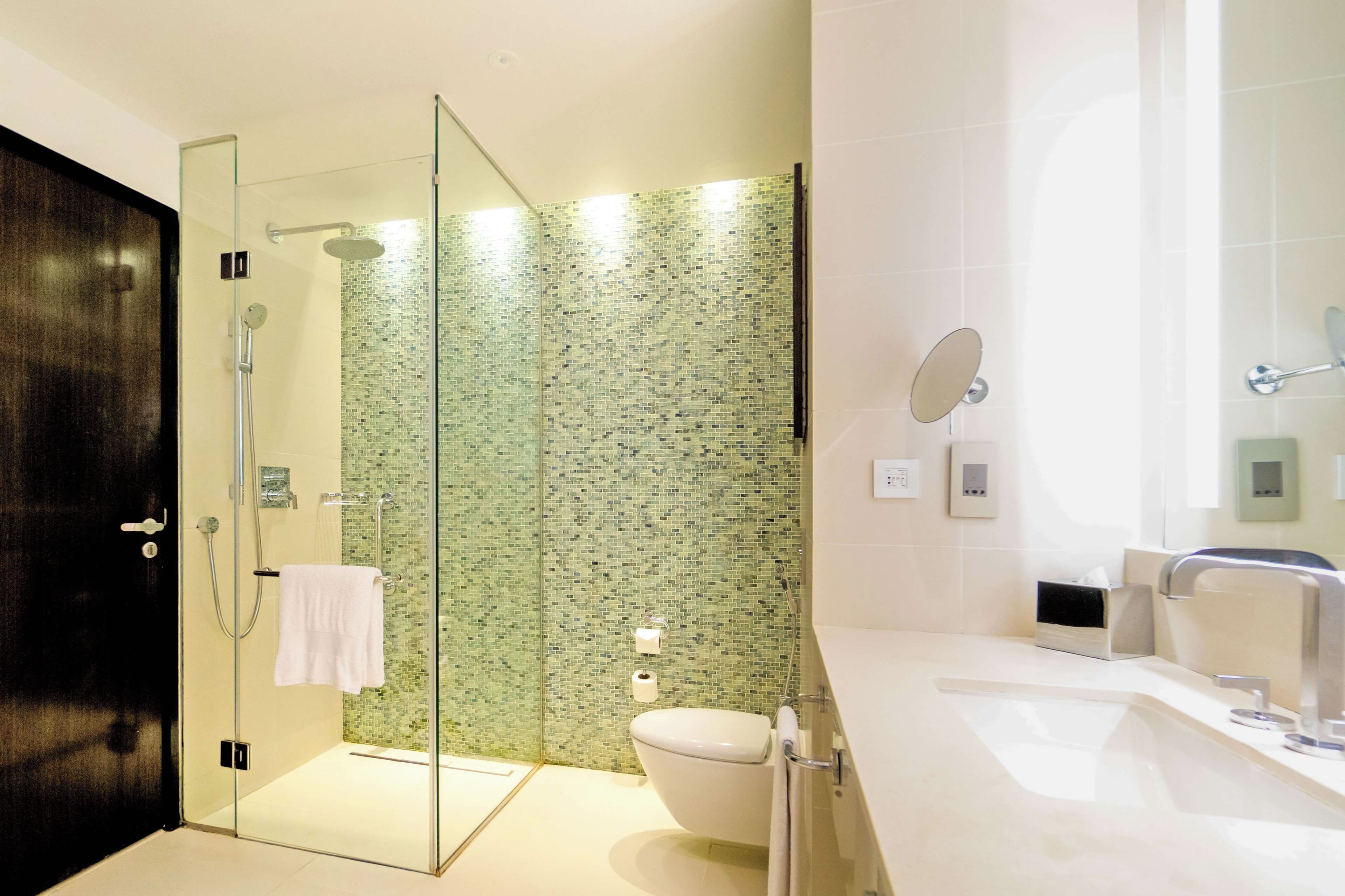 Een moderne badkamer met een glazen douchecabine, toilet en een wastafel met spiegel.