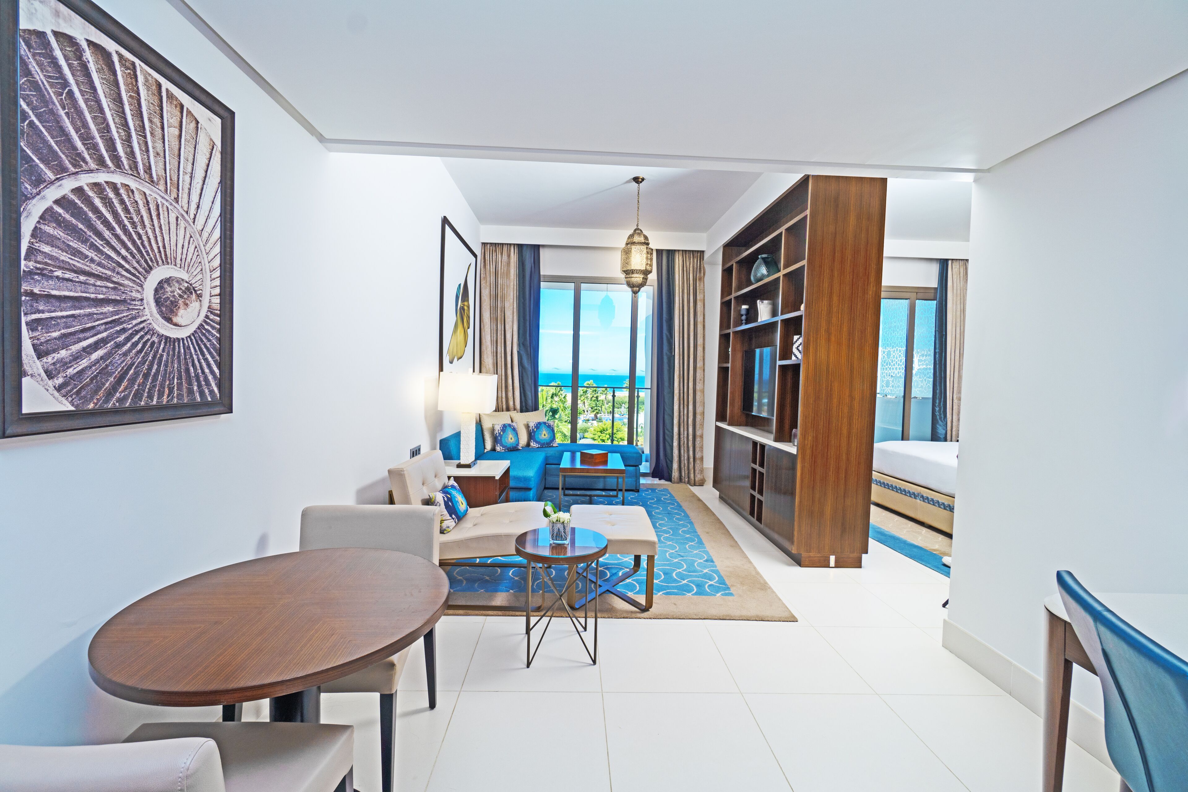 A modern living room with a sofa, coffee table, and a dining area with a table and chairs.