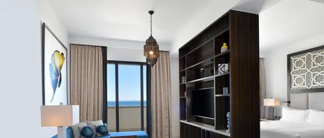 Una habitación de hotel moderna con una cama grande, un sofá, una mesita de centro, un televisor y una estantería.