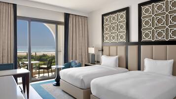 A hotel room with two beds, a balcony with a view of the beach, and decorative wall panels.